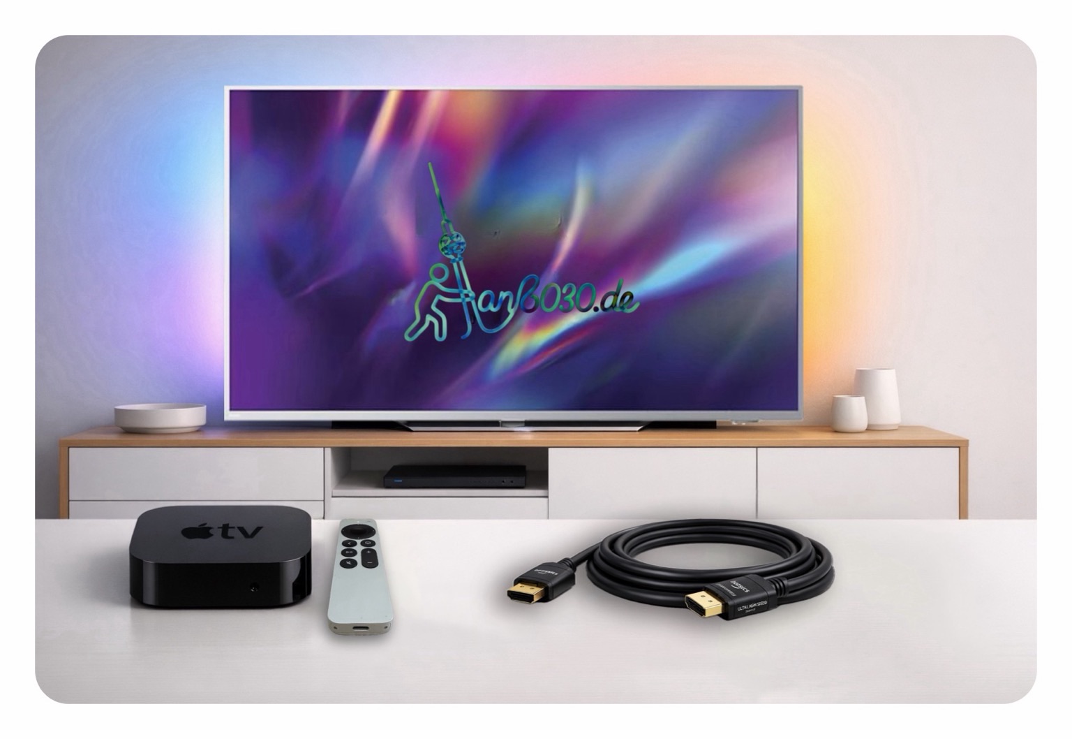 Titelbild: Ein modernes Heimkino-Setup: Ein Flachbildfernseher mit farbiger Ambilight-Hintergrundbeleuchtung steht auf einem Sideboard. Davor sind ein Apple TV mit Fernbedienung und ein HDMI-Kabel auf einer weißen Fläche angerichtet. Mittig auf dem TV-Bildschirm ist das Logo von „anb030.de“ zu sehen. 