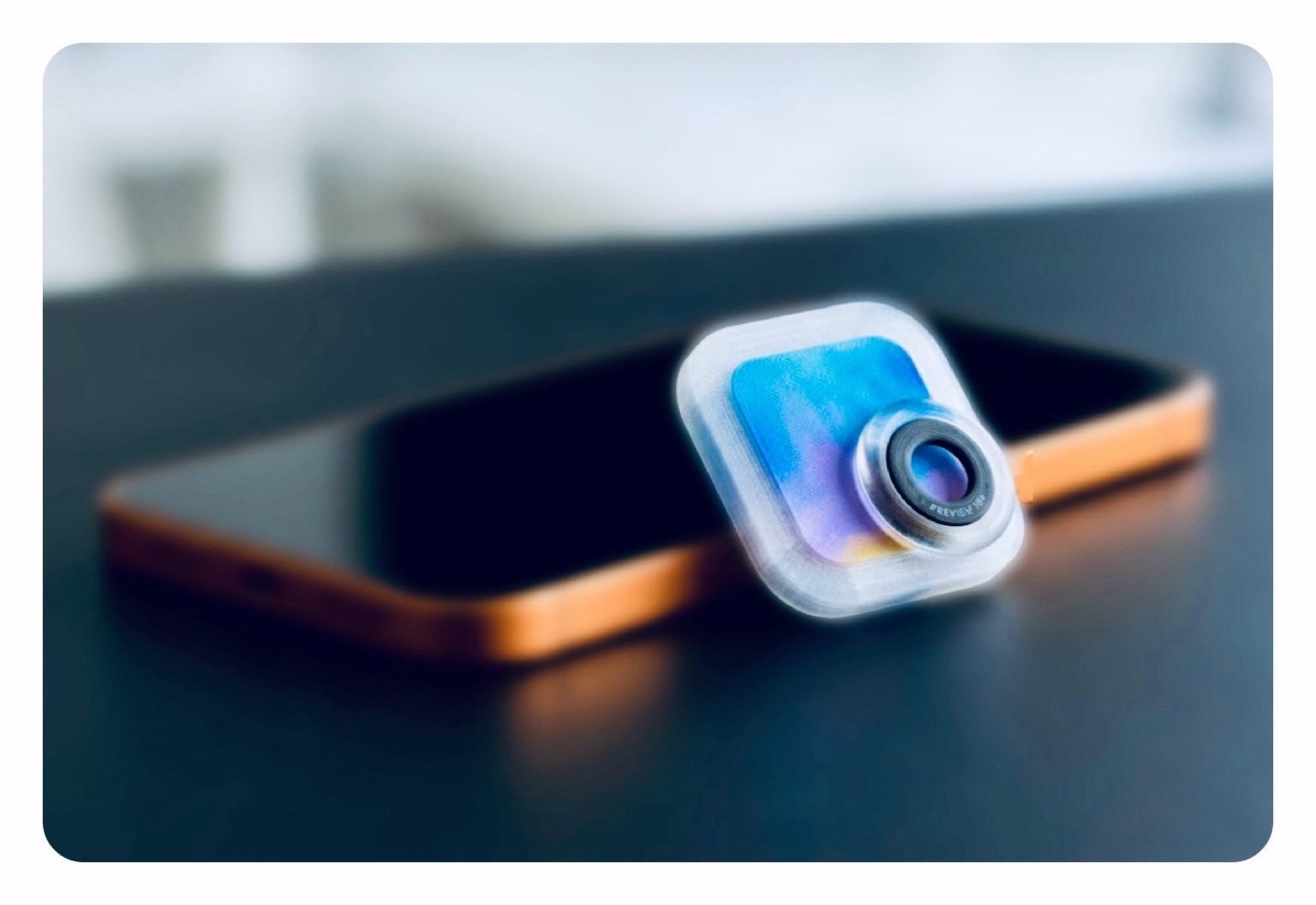 Titelbild: Zu sehen ist ein iPhone 17 Pro in Orange und ein ausgedrucktes App-Icon aus dem 3D-Drucker namens Vorschau-App, was an dem Smartphone lehnt.